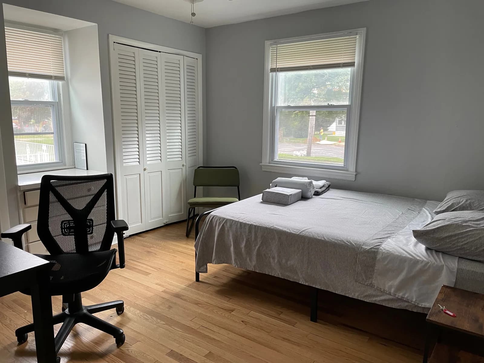 Furnished bedroom with a desk, chair, closet, and two windows.